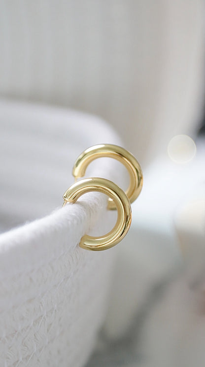 Gold hoop earrings on a white stand with a blurred background